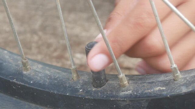 Hands opening and closing the valve of a bicycle tire