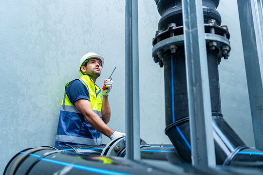 Industrial engineer using walkie talkie inspecting pipeline system in factory maintenance engineering operations technical inspection industrial equipment monitoring safety communication work process