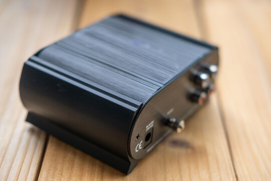 Black phono preamplifier with RCA connectors, ground terminal, power input jack, close-up view, High-fidelity audio equipment, Quality Essential gear for audiophiles, analog device for turntable
