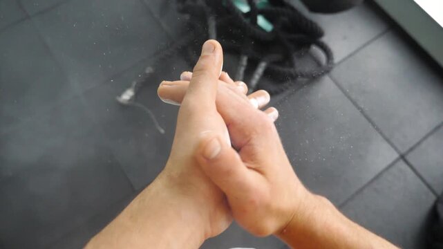 Hands covered in chalk dust, transitioning from open palms to a rubbing motion, creating a cloud of chalk particles, showcasing the preparation for an intense workout session