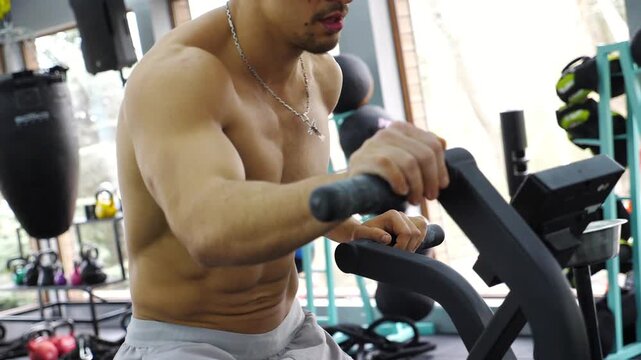 Male fitness enthusiast engaged in intense workout on exercise bike, showcasing determination and focus in a modern gym environment with vibrant equipment and natural light streaming through windows