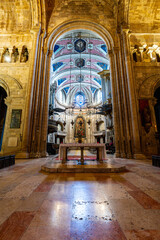 Obraz premium Historic cathedral interior with stone arches altar and decorative painted ceiling symmetrical perspective religious architecture and spiritual atmosphere in Lisbon