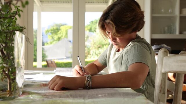 young boy doing homework on table at home