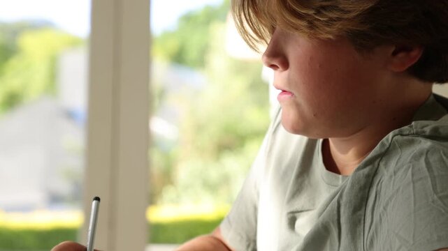 young boy doing homework on table at home