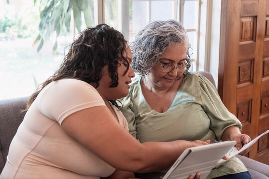 Young woman assisting senior with digital literacy on tablet
