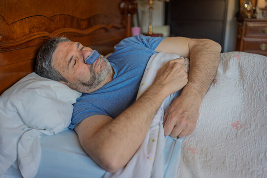 Man peacefully asleep, using a nasal dilator for better breathing, decreased snoring, and to avoid sleep apnea