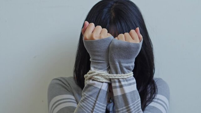 Young woman with hands tied with rope for concept of human trafficking and kidnapping