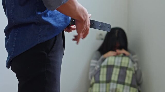 Close up of kidnapper hands taking off belt to strike crying female victims