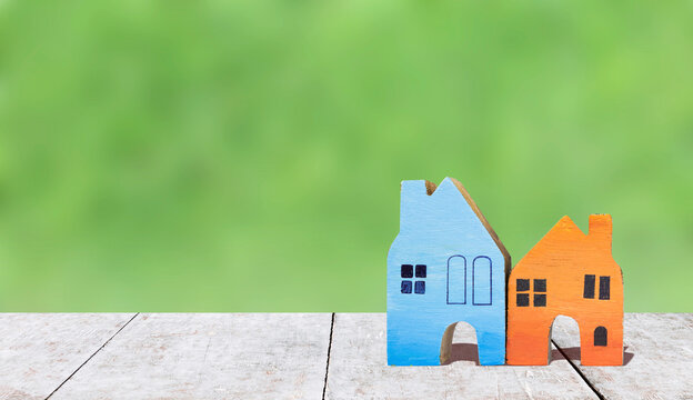 Colourful wooden house model over blurred natural green background, property and real estate business concept, property investment, summer holiday house