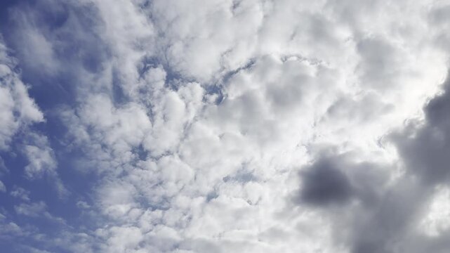 Dynamic camera transition from a clear blue sky to thick dark rain clouds. Contrasting weather change, cloud movement, and pre-storm atmospheric conditions