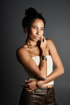 Elegant African American woman shining in golden jewelry against a studio backdrop