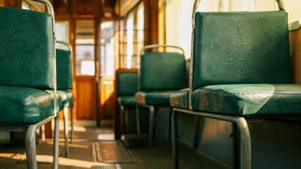Interior view of an old tram with green seats and sunlight streaming through windows © shine.graphics