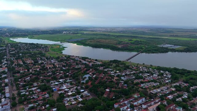 Sweeping drone view capturing the urban expanse of Posadas, Argentina, with the Ulises Lopez and Chacabuco bridges crossing the vast Parana River.