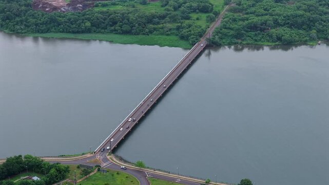 Cinematic drone footage looking down at cars driving across the Ulises Lopez Bridge over the vast Parana River in Misiones, Argentina.
