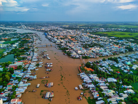 Aerial view of the river with floating houses and urban buildings along the banks under a blue sky in Chau Doc, An Giang, Vietnam.