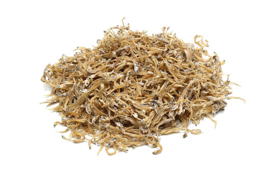 A pile of dried anchovies (ikan teri medan) isolated white background. the textured details of the naturally dried small fish. culinary content, traditional cooking ingredients, seafood markets