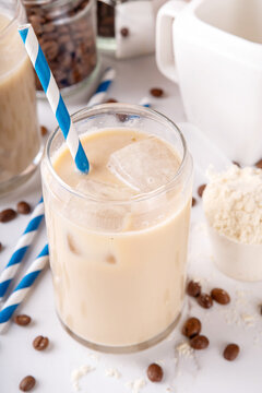 Iced protein coffee, whey isolate latte drink with whey protein powder in scoop and coffee beans, on kitchen table copy space