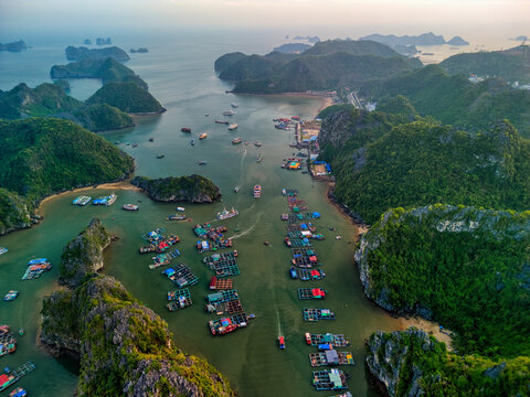 Aerial view of Cat Ba Archipelago with floating fish farms and boats nestled between lush limestone islands, Ha Tu, Hai Phong, Vietnam.