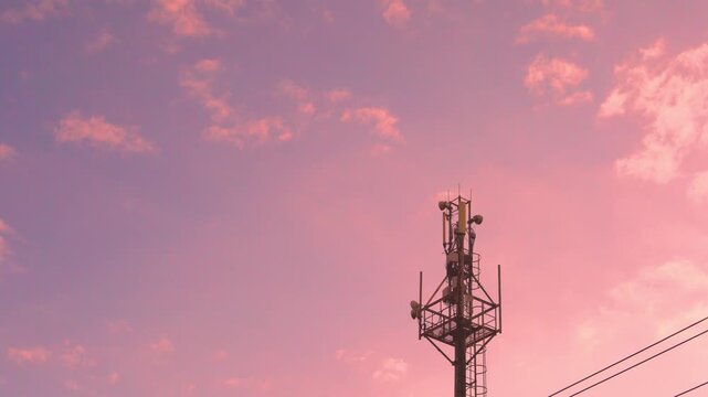 Cellular GSM tower close-up, cellular antenna, cell tower closeup, mobile communication station and beautiful colorful aerial view pink blue sky and fluffy clouds at sunset time lapse.