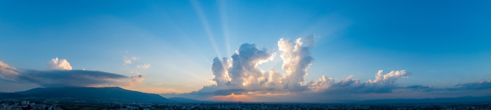 Cinematic Panorama of Sun Rays Breaking Through Clouds over a City Skyline