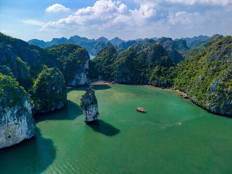 Aerial view of Cat Ba Archipelago with limestone karsts rising from emerald waters and a small boat near a rock pillar Ha Tu, Hai Phong, Vietnam.
