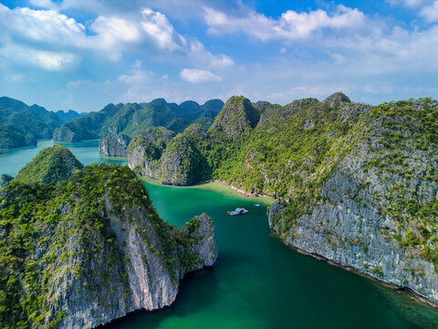 Aerial view of Cat Ba Archipelago featuring limestone karsts, lush green vegetation, and turquoise waters under a blue sky in Ha Tu, Hai Phong, Vietnam.