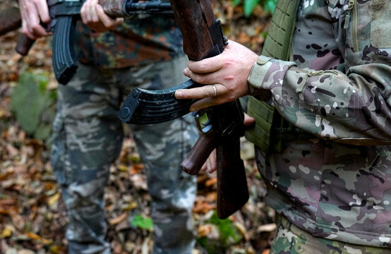 Soldiers in Camouflage Holding Assault Rifles in Forest. Close-up of soldiers in tactical gear and multicam uniforms holding automatic rifles while standing on a forest path covered in autumn leaves
