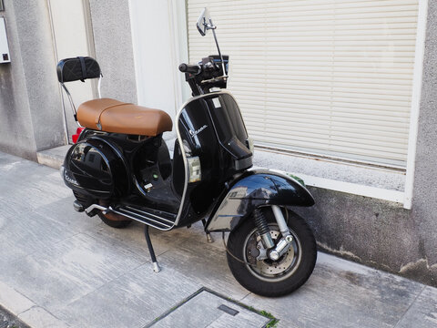 TOKYO, JAPAN - April 14, 2026: A Vespa scooter parked by a modern building in Tokyo.