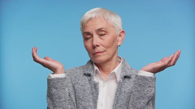 Senior woman weighing options with raised hands on blue