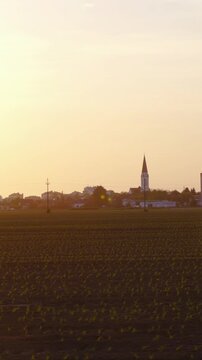 Driving beside a farm field with city and sunset in background