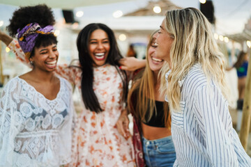 Obraz premium Multiracial happy women friends dancing at beach party with dj playing music in background - Summer events and vacation concept - Soft focus on right girl hair