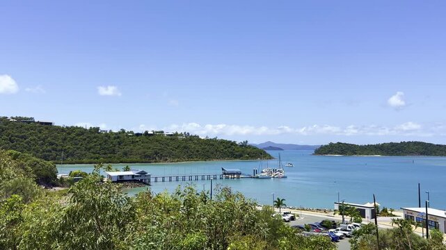 Sunny coastal scene at Shute Bay, Queensland, Australia. White sandy beach and turquoise Pacific waters with tropical landscape, calm sea, and idyllic travel destination.