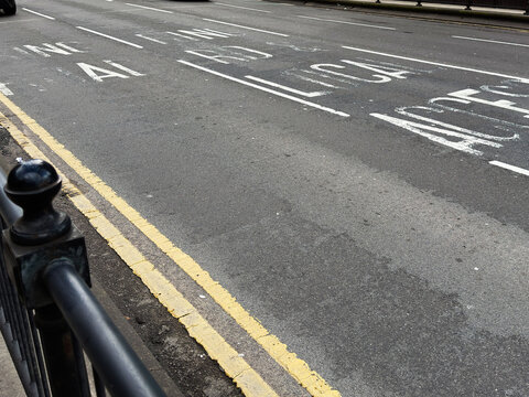 Empty urban street with double yellow lines and faded road markings in Manchester UK showing pavement railing and asphalt textures