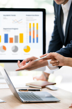 Professional business partners analyzing complex financial dashboard and colorful charts on laptop in a modern office.