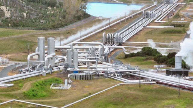 Steam billows from geothermal power plant pipes in Wairakei, New Zealand, showcasing renewable energy production.