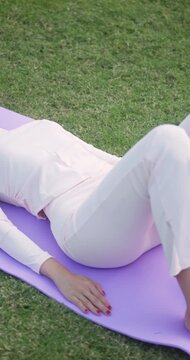 Young woman doing glute bridge exercise on yoga mat in garden.