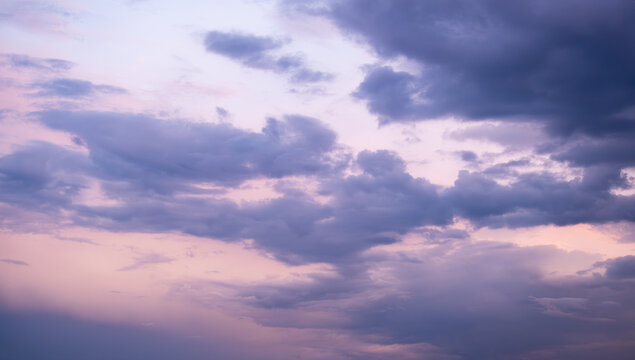 Purple clouds on pink sky at sunset or sunrise, soft twilight colors creating calm atmospheric background