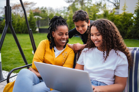 African American family bonding outdoors enjoying laptop together