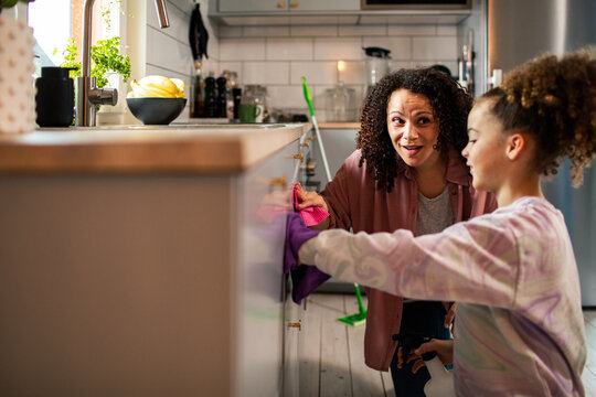 Mother and daughter cleaning kitchen cabinets at home