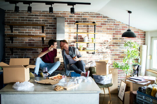 Couple eating pizza while unpacking in new apartment kitchen