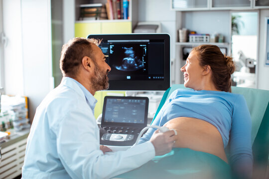 Doctor performing prenatal ultrasound with pregnant woman in clinic