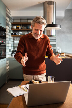 Smiling mature man on video call in home kitchen