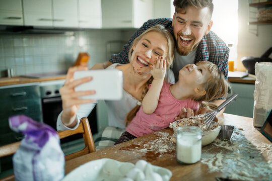 Happy family baking and taking selfie in home kitchen