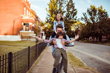 Obraz premium Father playing with two children on neighborhood sidewalk