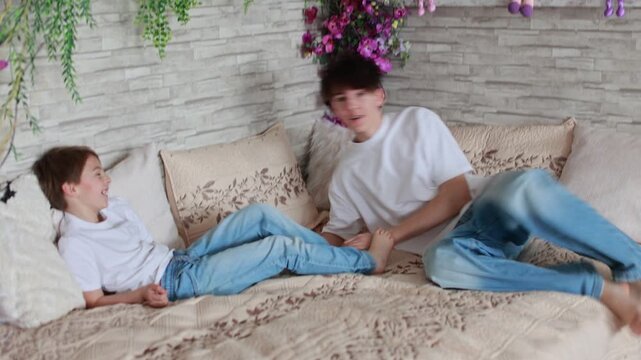Happy positive children, tickling on the feet, having fun together, boy brothers at home having wonderful day with joy