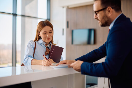 Happy businesswoman signing documents at office reception while arriving for job interview.