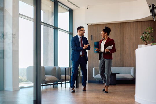 Happy business colleagues communicating while working in office.