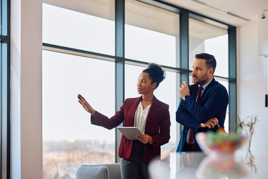 Corporate managers talking while using digital tablet in office.