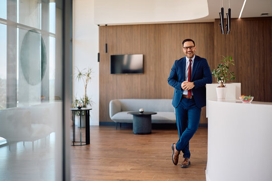Happy businessman working in corporate office and looking at camera.