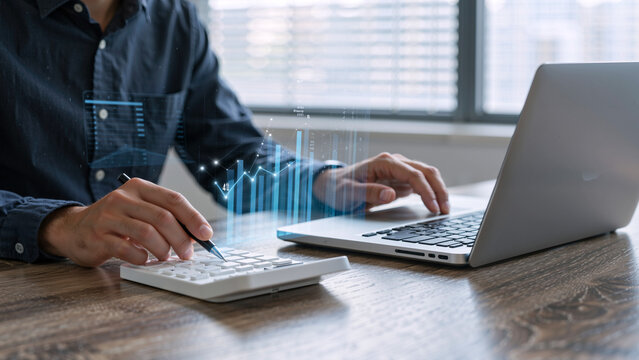 Man using calculator and laptop with financial charts